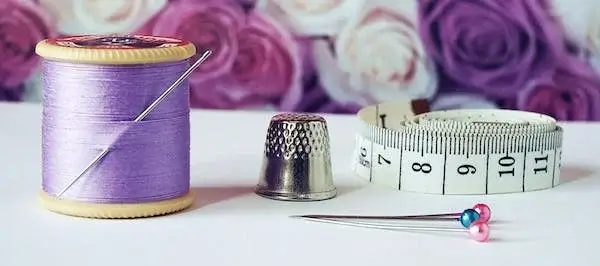 Photo of needle and purple thread, Thimble and tape Measure