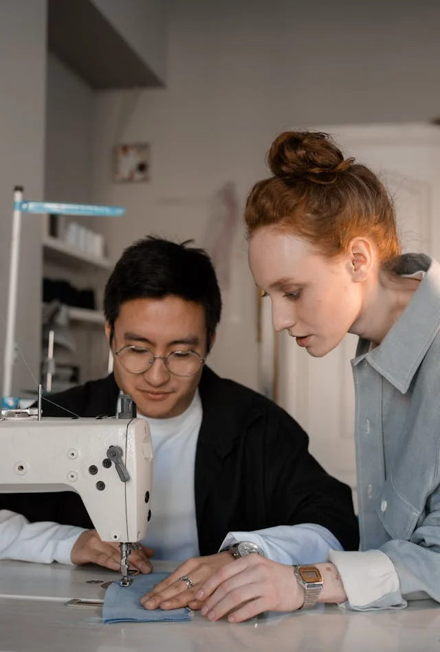 Woman showing a man how to sew on a sewing machine